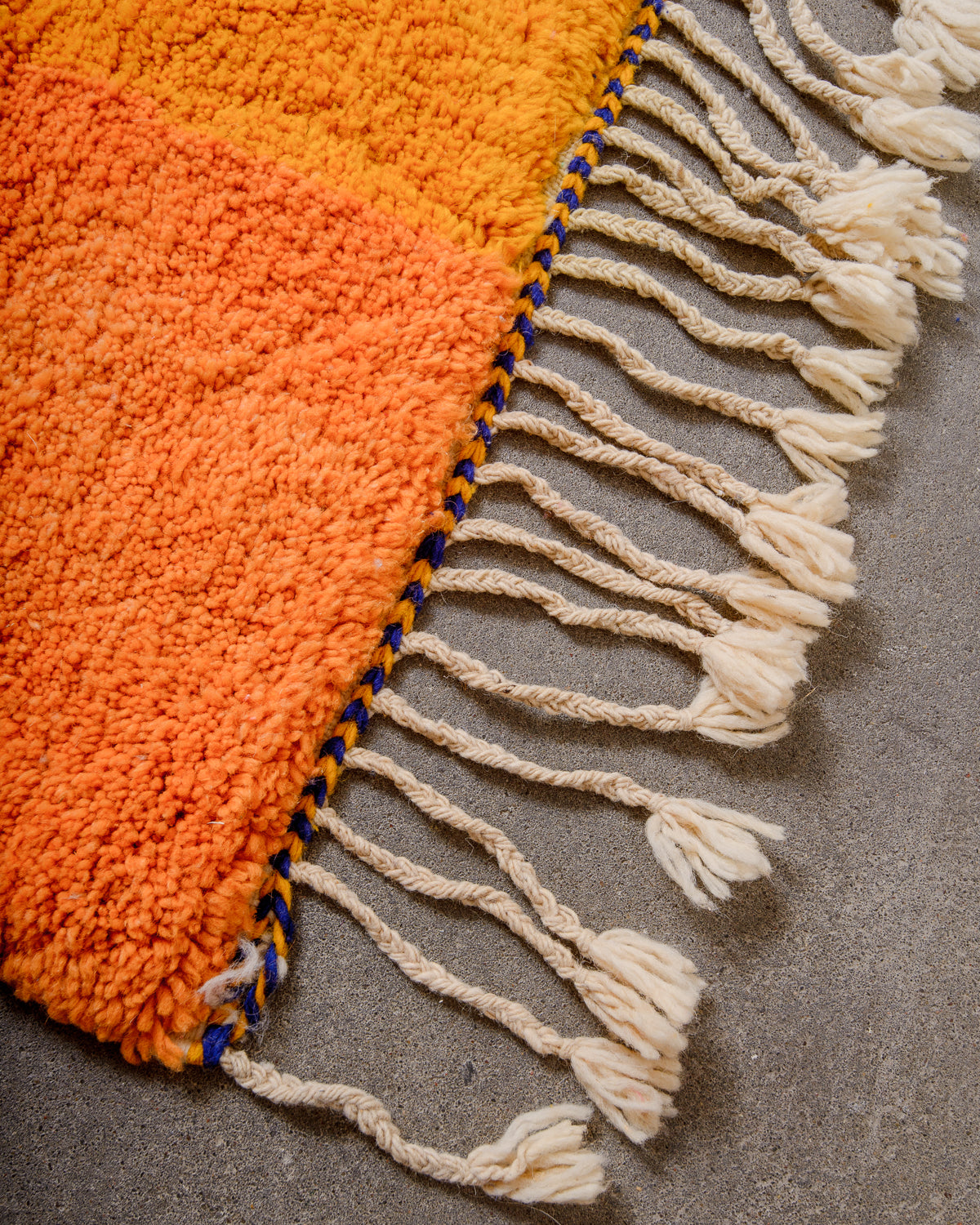 Corner of rug made of thick wool pile and natural wool tassels.